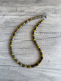 DLD Jewelry mens beaded gemstone necklace with one strand of alternating olive green jade and brown wood drum shaped beads laying on a wood surface.