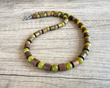 DLD Jewelry mens beaded gemstone necklace with one strand of alternating olive green jade and brown wood drum shaped beads laying on a wood surface.