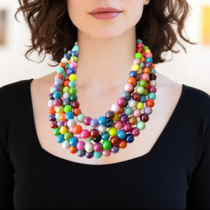 Colorful 5 strand big beaded necklace worn by a person against a neutral background