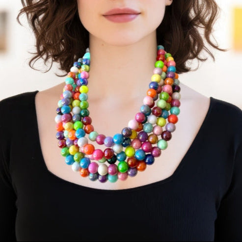 Colorful 5 strand big beaded necklace worn by a person against a neutral background