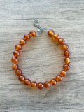 Betty chunky bead necklace with glossy amber brown acrylic beads and a silver-tone clasp on wood