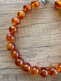 Close-up of glossy, translucent amber brown acrylic beads on wood