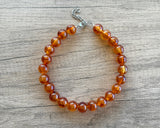 Betty chunky bead necklace with glossy amber brown acrylic beads and a silver-tone clasp on wood