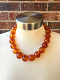 Betty amber brown acrylic beaded choker displayed on a white mannequin against a brick wall