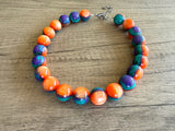 Betty chunky bead necklace with glossy orange, teal and purple acrylic beads and a silver-tone clasp on wood