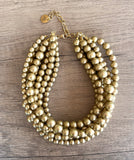 Alana 7 strand chunky beaded choker necklace with matte beads in different  sizes and a gold-tone clasp on wood