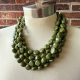 Green beaded necklace on a mannequin neck against a brick wall background
