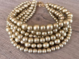Alana multi strand chunky beaded choker necklace with matte beads in different  sizes and a gold-tone clasp on wood. 