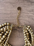 Close up of gold clasp on Alana 7 strand chunky beaded choker necklace with matte beads on wood 