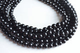 A beaded multi strand statement necklace made with shiny black acrylic beads.