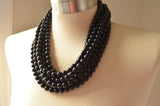A beaded multi strand statement necklace made with shiny black acrylic beads.