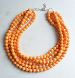 A beaded multi strand statement necklace made with yellow orange lucite beads. 