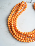 A beaded multi strand statement necklace made with yellow orange lucite beads. 