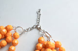 A beaded multi strand statement necklace made with yellow orange lucite beads. 