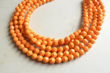 A beaded multi strand statement necklace made with yellow orange lucite beads. 