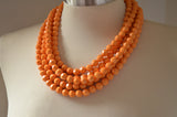 A beaded multi strand statement necklace made with yellow orange lucite beads. 